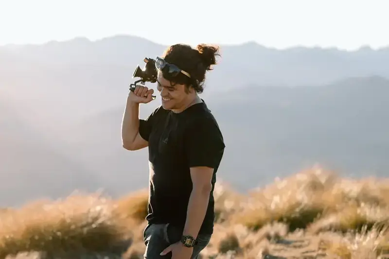 Cristian Batista filming with cinema camera in Queenstown mountains
